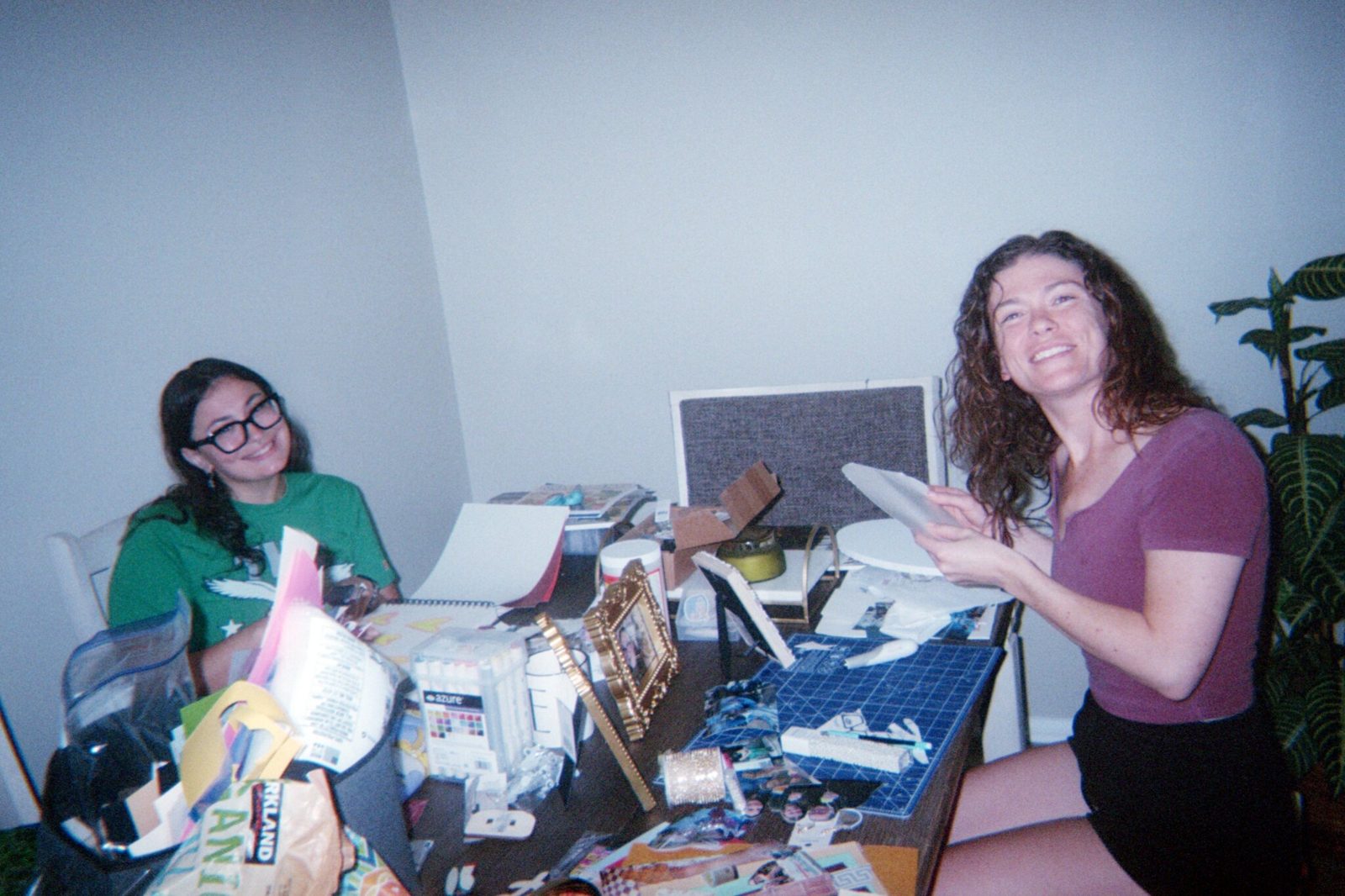 Two people smiling at a table covered in craft supplies